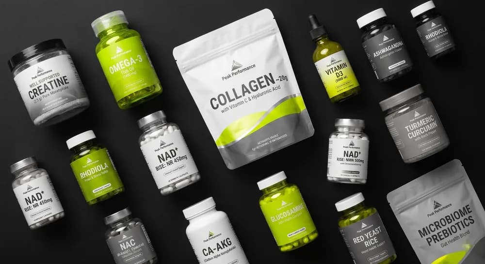 Flat-Lay der Blueprint-Stack-Wirkstoffe — Kreatin, Omega-3, Kollagen, NMN/NR, Ca-AKG, Curcumin, Microbiome-Prebiotika auf dunklem Grund